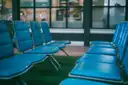 Filas de asientos acolchados de color verde azulado en una sala de espera tranquila de aeropuerto
