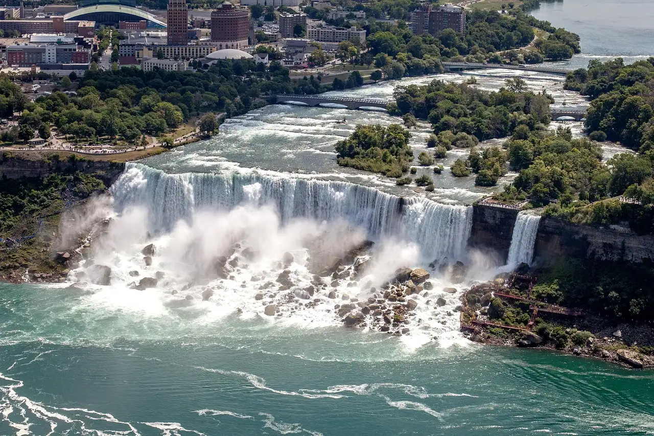 Las cataratas Americanas y los rápidos que hay encima, vistos desde lo alto, con una ciudad detrás
