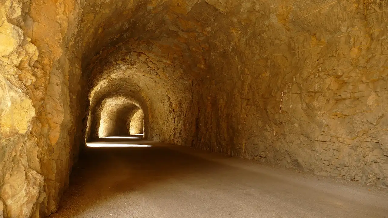 Un túnel iluminado, excavado en roca amarilla
