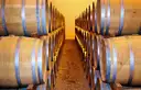 Filas de barricas de roble apiladas en una bodega