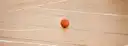 Un balón de baloncesto naranja en el suelo de madera de una pista cubierta vacía
