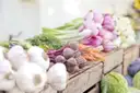 Ajos, remolachas y zanahorias en cajas en un puesto de un mercado de productores