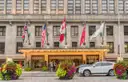 La fachada de piedra del hotel Royal York en Front Street, con banderas, una marquesina iluminada en la entrada y jardineras con flores delante.