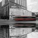 Un tranvía rojo y blanco de Toronto pasa desenfocado por el movimiento en una calle del centro, reflejado en un charco.