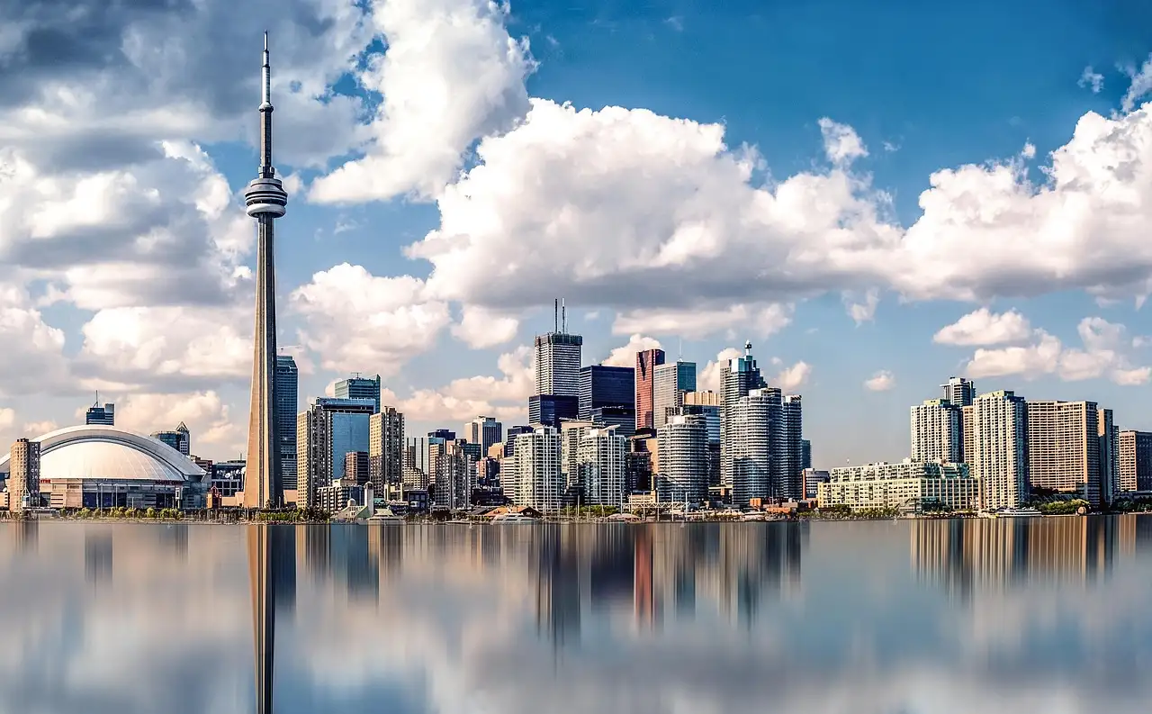 El centro de Toronto y la Torre CN bajo nubes blancas, reflejados en el agua en calma