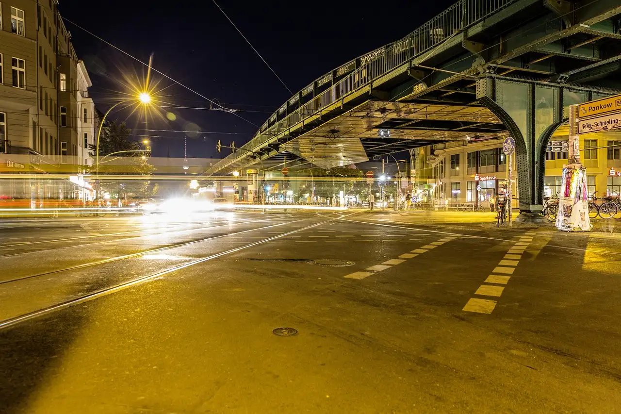 Elevated U-Bahn viaduct over a quiet Berlin street crossing at night under yellow streetlights