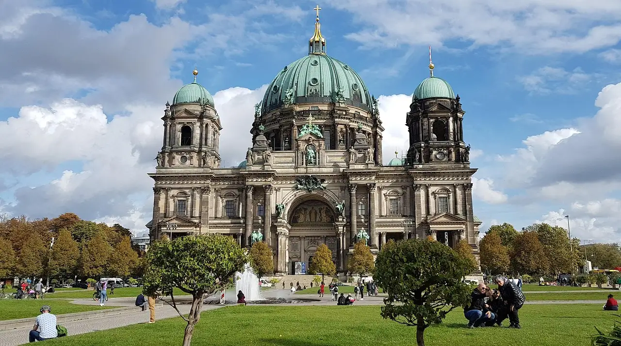 Berlin Cathedral with its green domes behind the lawns of the Lustgarten on a sunny day with clouds