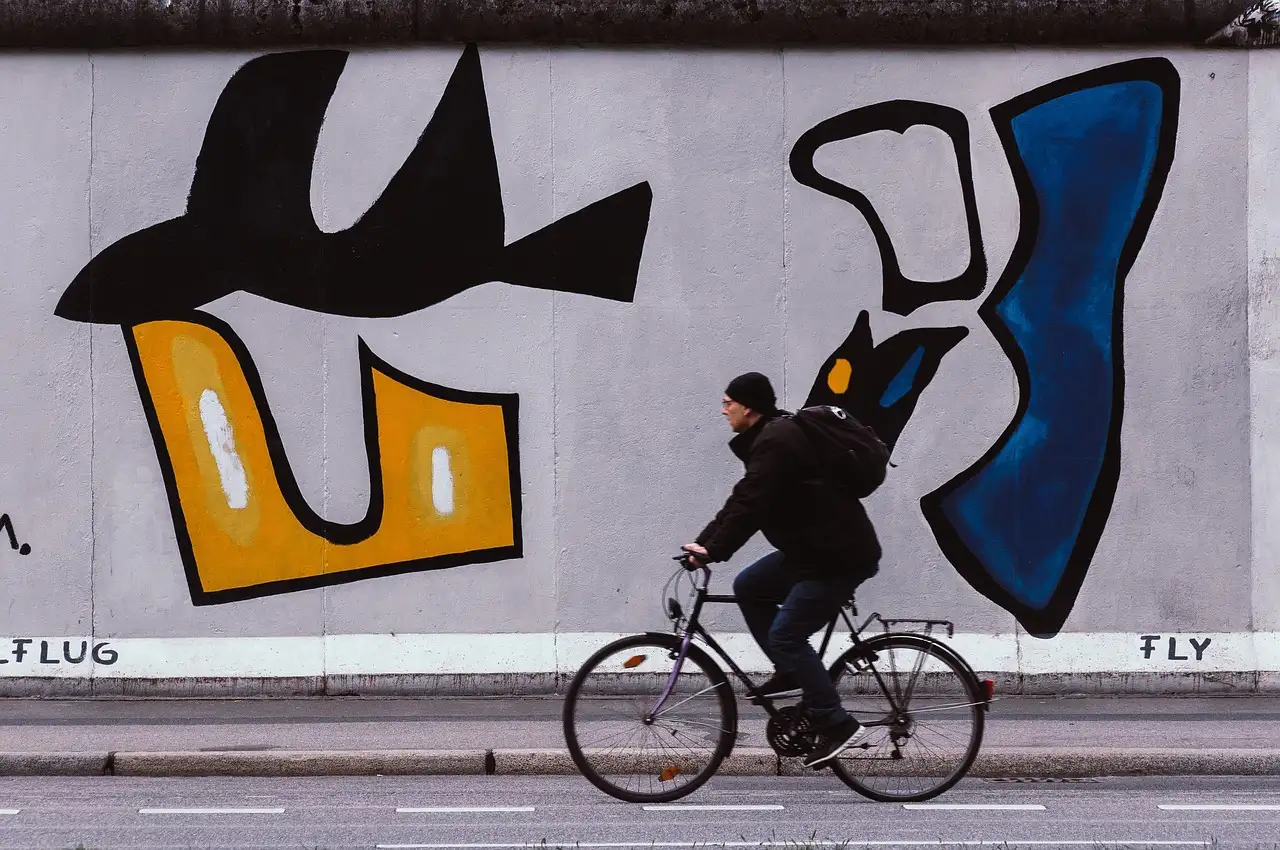 A cyclist riding past a painted stretch of the Berlin Wall