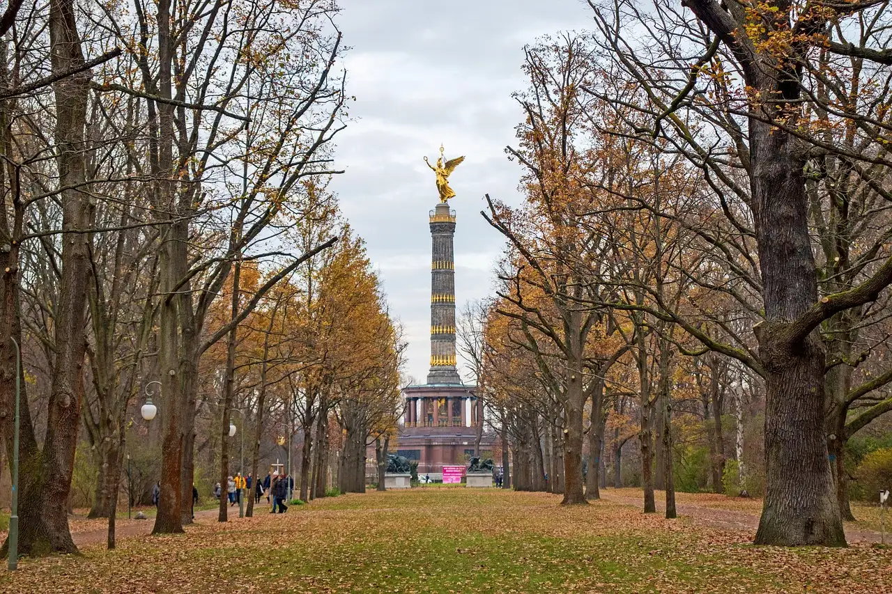 Autumn trees in the Tiergarten lining a lawn that leads to the golden Victory Column