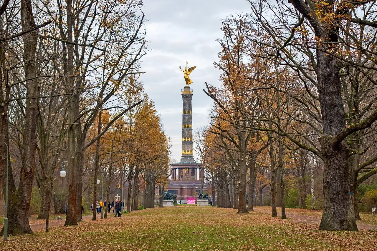 Autumn trees in the Tiergarten lining a lawn that leads to the golden Victory Column