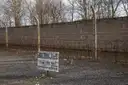 The grey camp wall with posts and wire at the Sachsenhausen Memorial, with a sign in front