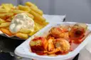Currywurst pieces in sauce next to fries with mayonnaise on a white tray