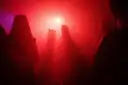 A crowd dancing in a club under red light, seen from behind