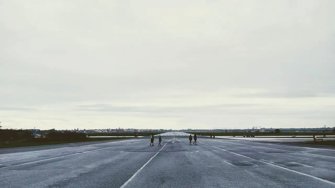 The wide former runway of Tempelhof airfield under a grey sky, with a few distant people