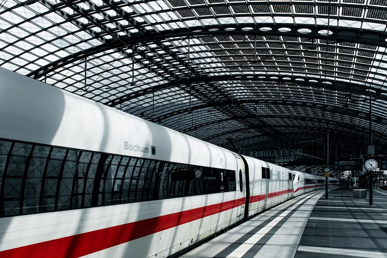 A white ICE train with a red stripe standing under the glass roof of Berlin Hauptbahnhof