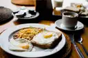 A breakfast plate with eggs and toast next to a cup of coffee