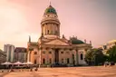 The French Cathedral on Gendarmenmarkt in Berlin in warm evening light, with café umbrellas on the square
