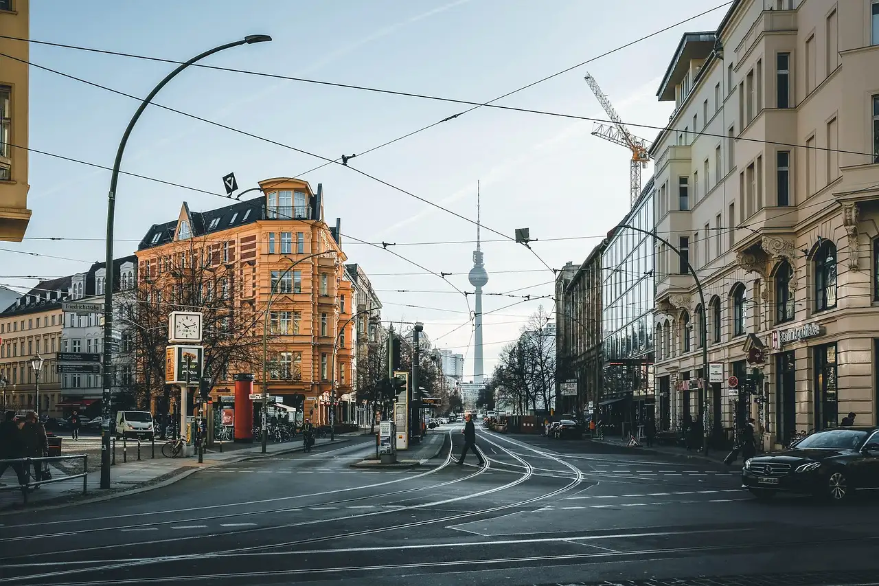 A Berlin street of old apartment buildings, with tram wires and the TV Tower behind