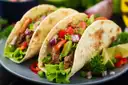 Two soft tacos filled with meat and fresh vegetables