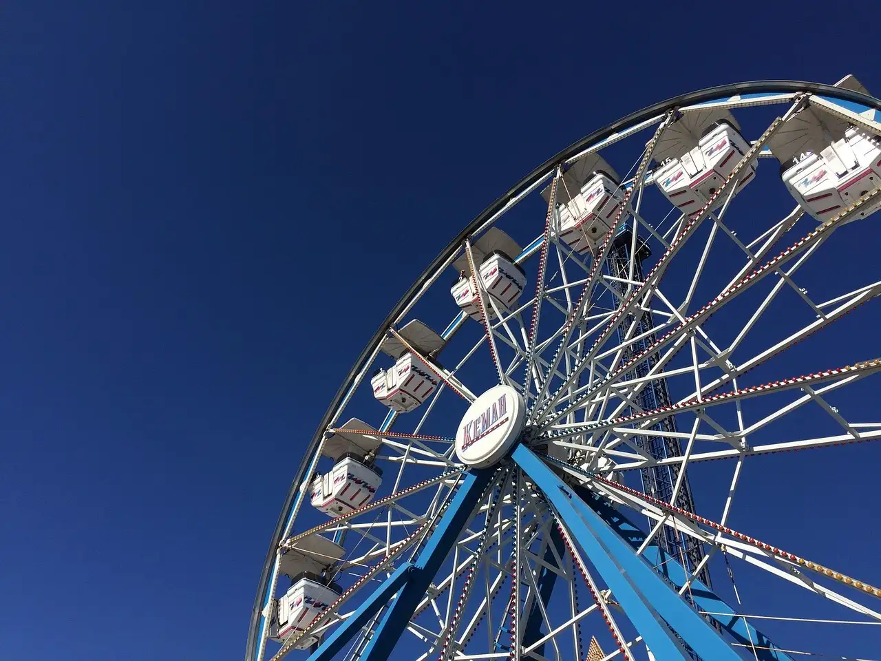 A Ferris wheel seen from below against a blue sky at the Kemah Boardwalk