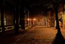 A dark city street at night under street lamps