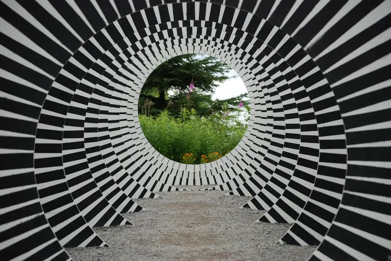 A black-and-white striped ring that looks like a tunnel, an optical illusion in a garden