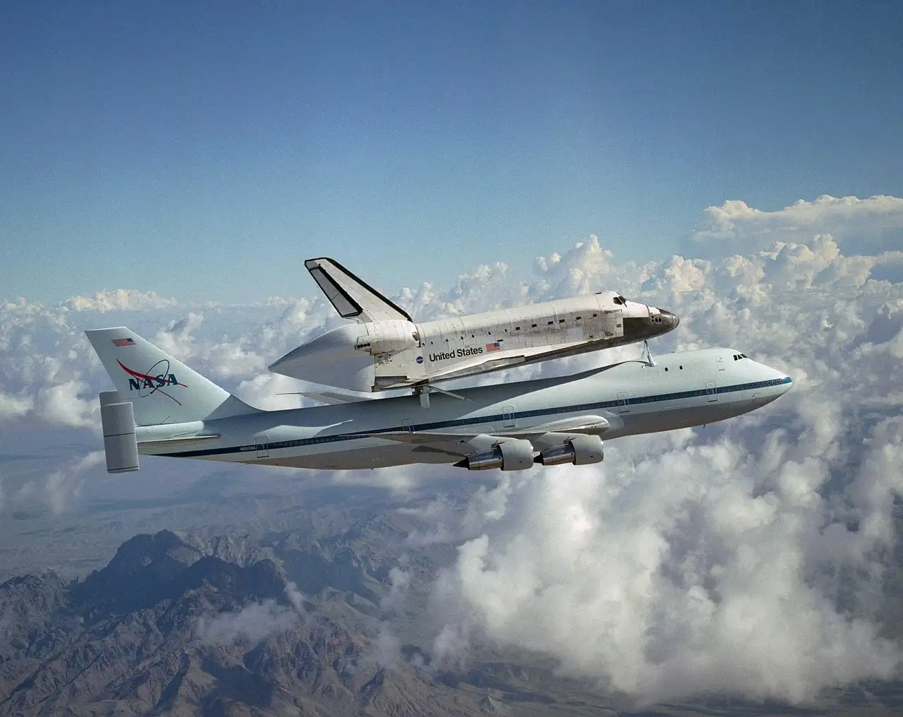 A NASA space shuttle riding on top of its Boeing 747 carrier aircraft above clouds; a stand-in for Houston's space attractions