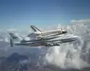 A NASA space shuttle riding on top of its Boeing 747 carrier aircraft above clouds; a stand-in for Houston's space attractions