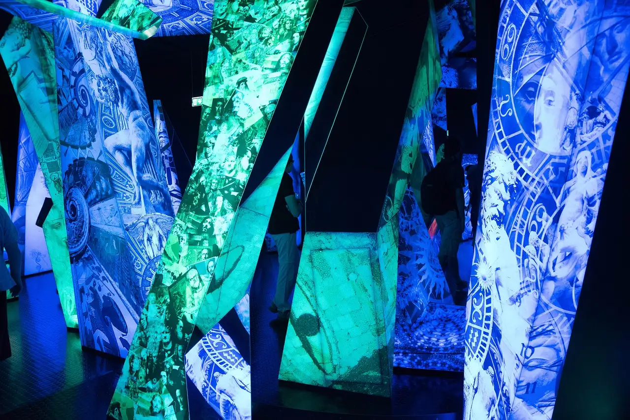 Tall panels glowing with projected blue and green art in a dark room