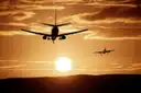 Two passenger planes silhouetted against a low orange sunset, a general airport photo and not a picture of a Houston airport