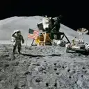 An astronaut saluting next to the US flag and a lunar module on the Moon