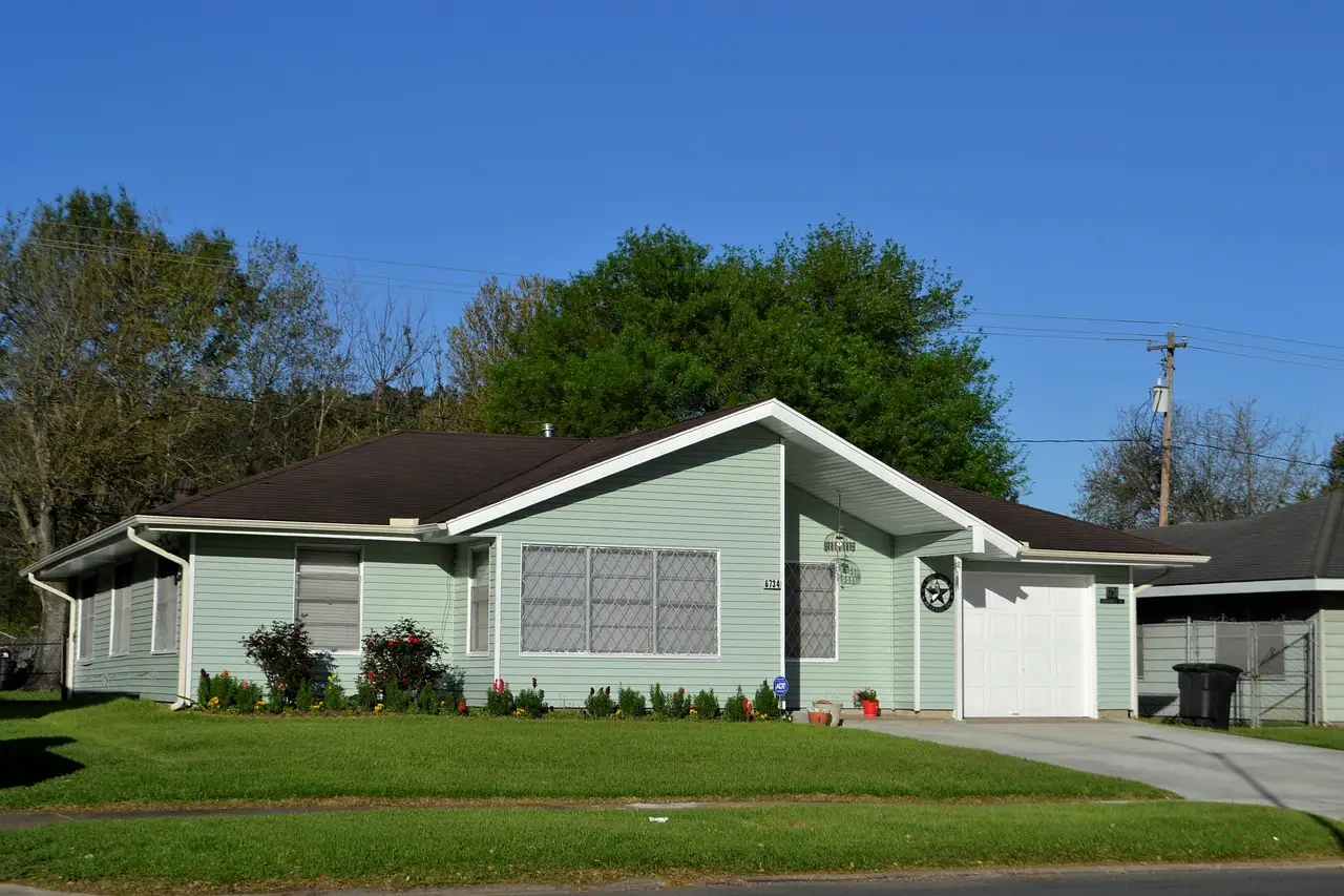 A single-storey house with a green lawn and trees on a Houston residential street