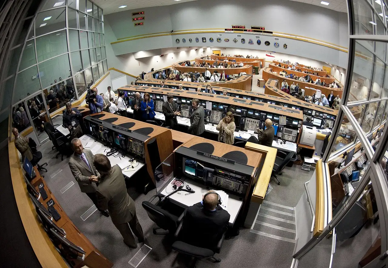 A NASA control room with rows of desks and screens, seen through a wide-angle lens