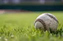 A baseball resting on green grass in a ballpark