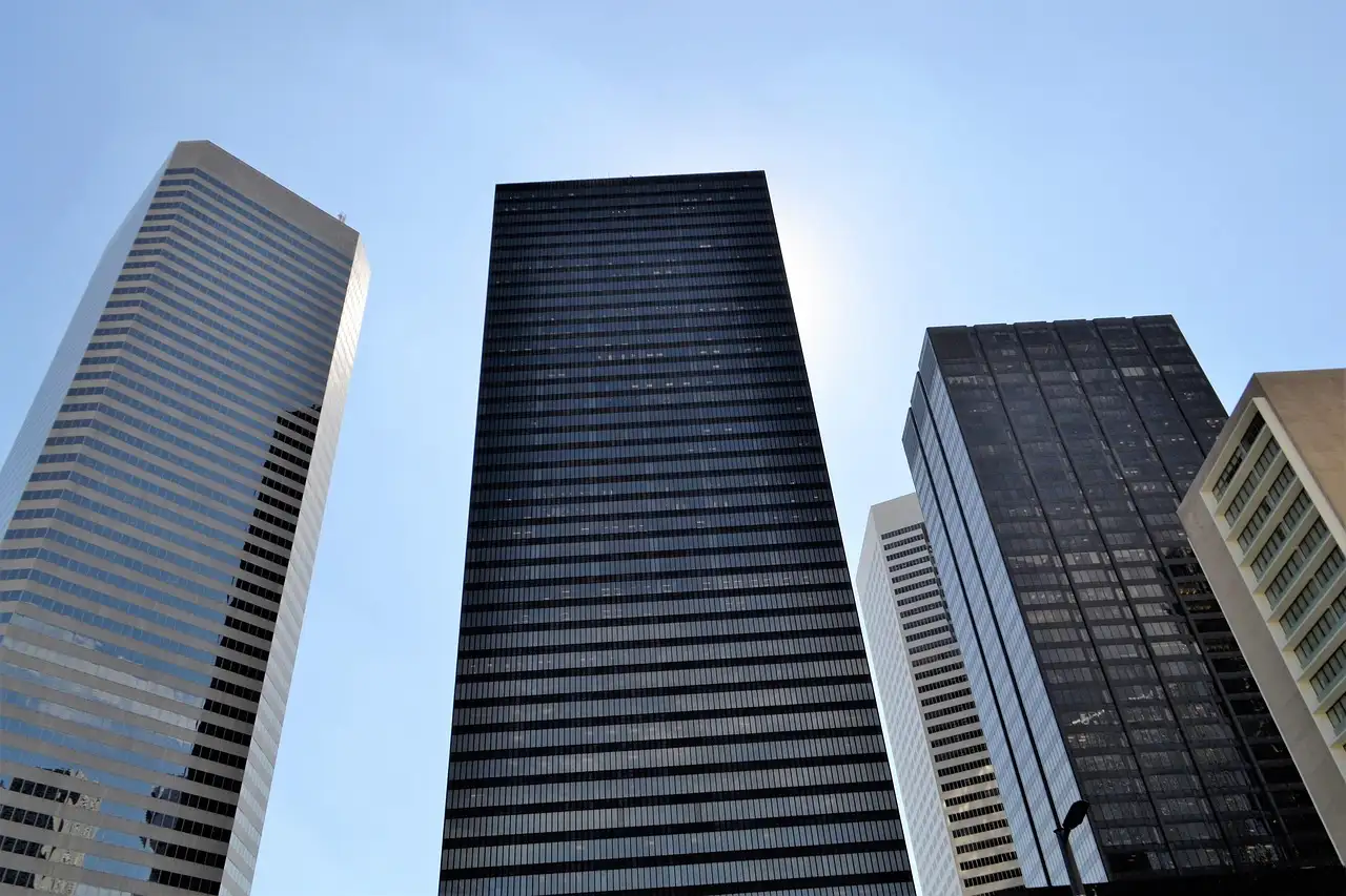 Dark glass office towers in downtown Houston seen from below against a blue sky