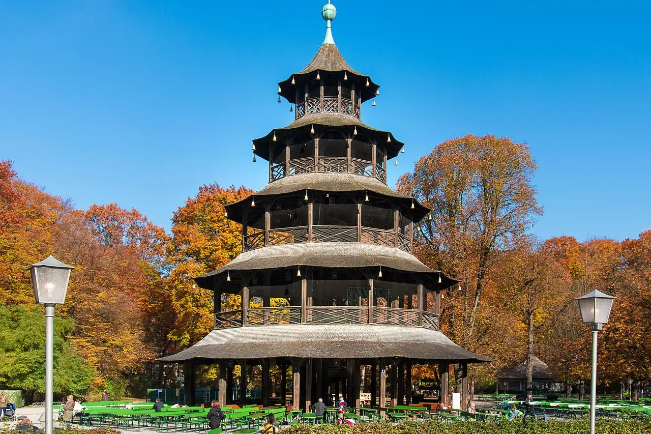 The wooden Chinese Tower in the English Garden, with beer garden tables and autumn trees