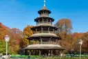 The wooden Chinese Tower in the English Garden, with beer garden tables and autumn trees