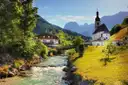 The church of Ramsau by a mountain stream, with rocky peaks behind