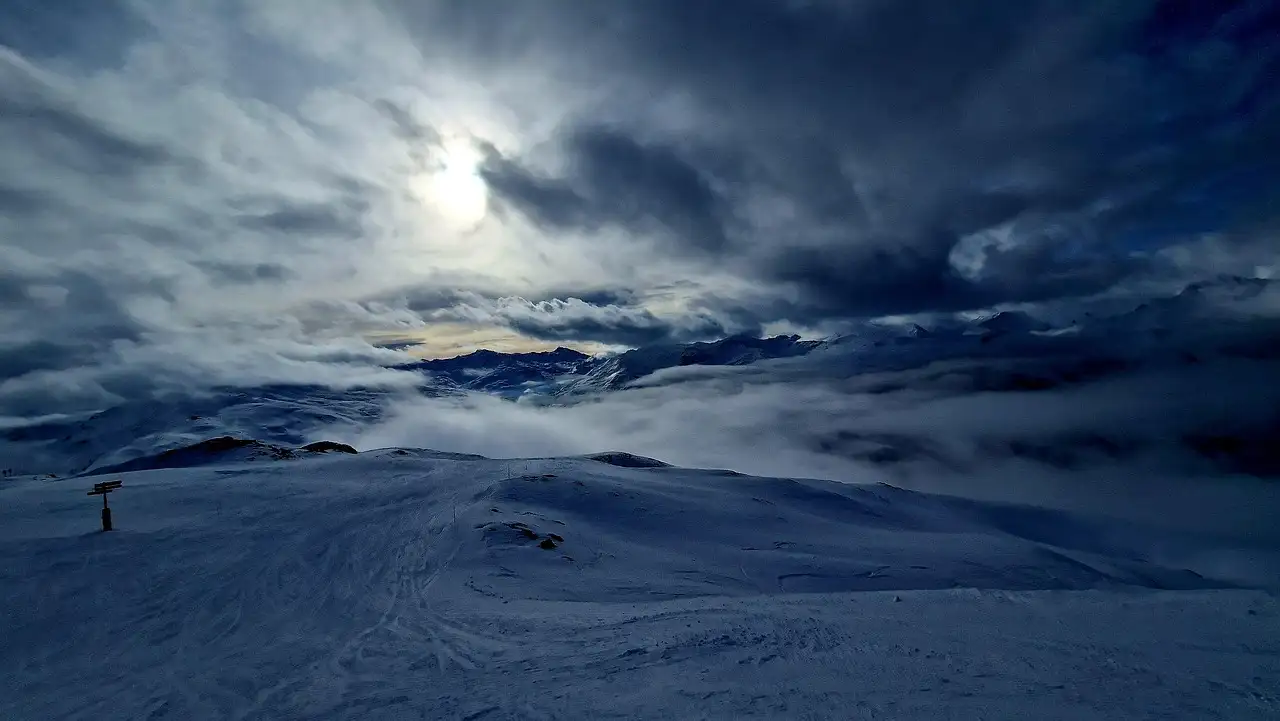 Snow-covered mountain slopes under a dark, cloudy sky