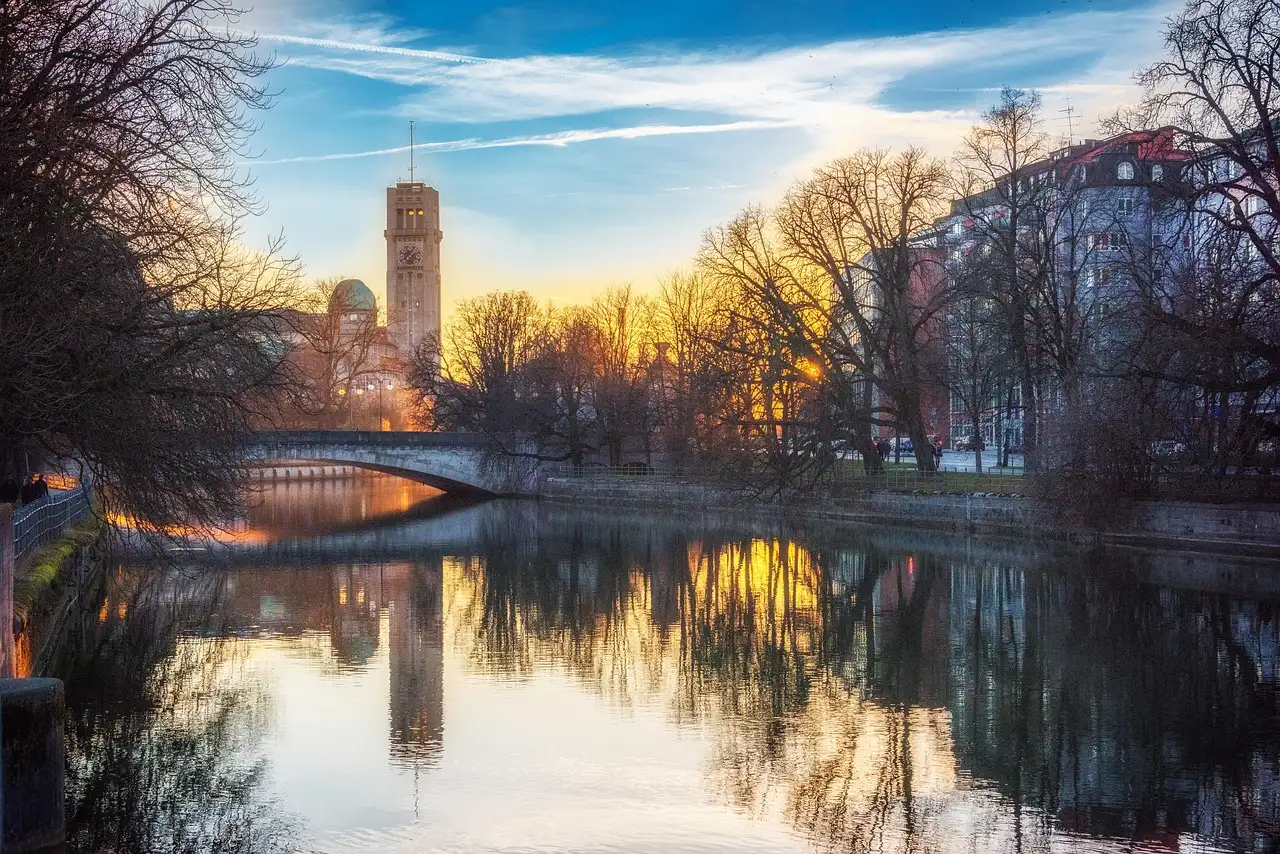 The Isar river in Munich at sunset, with a bridge and a tall square tower on the far bank