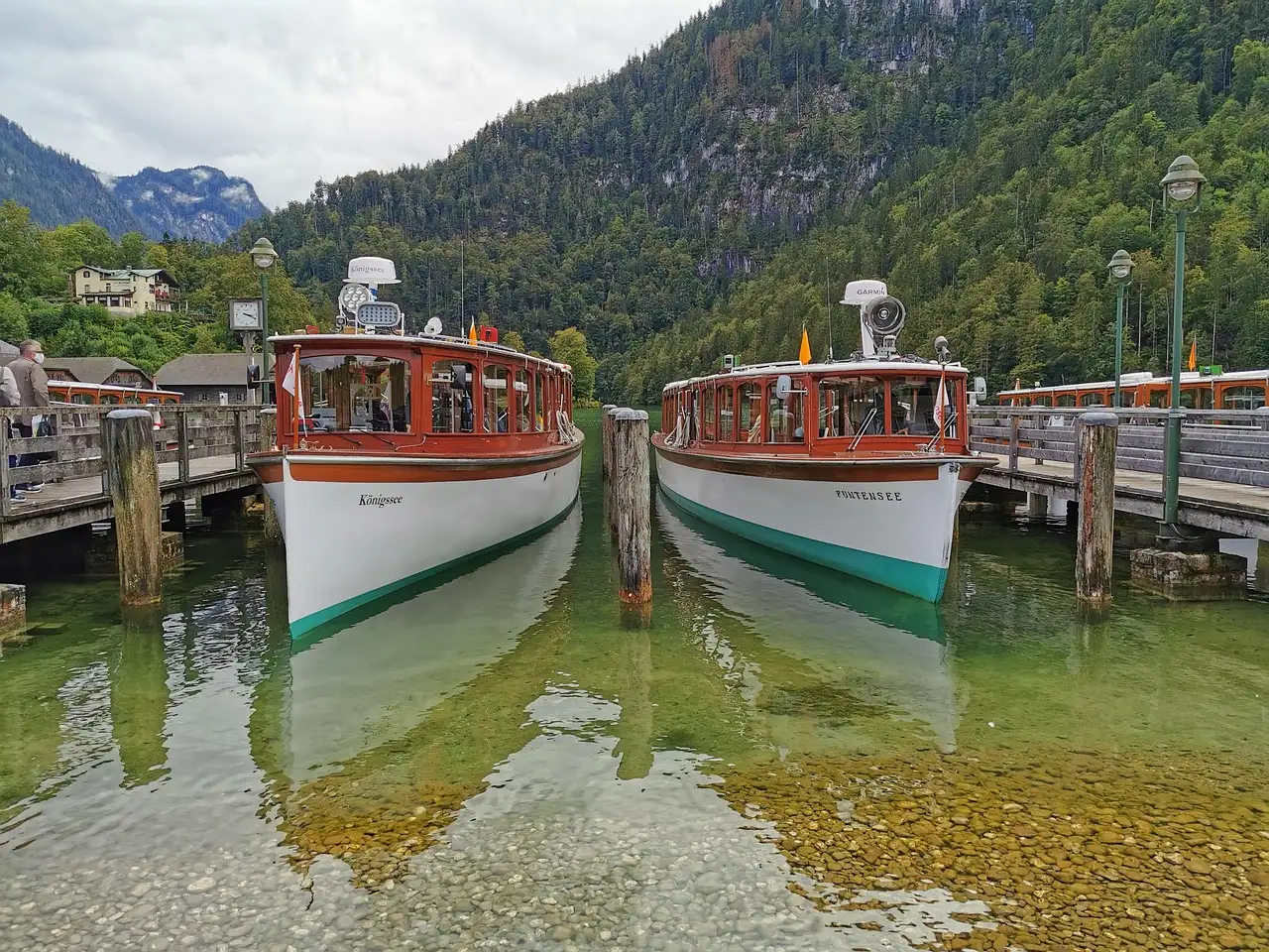 Two wooden passenger boats moored at a dock on Lake Königssee