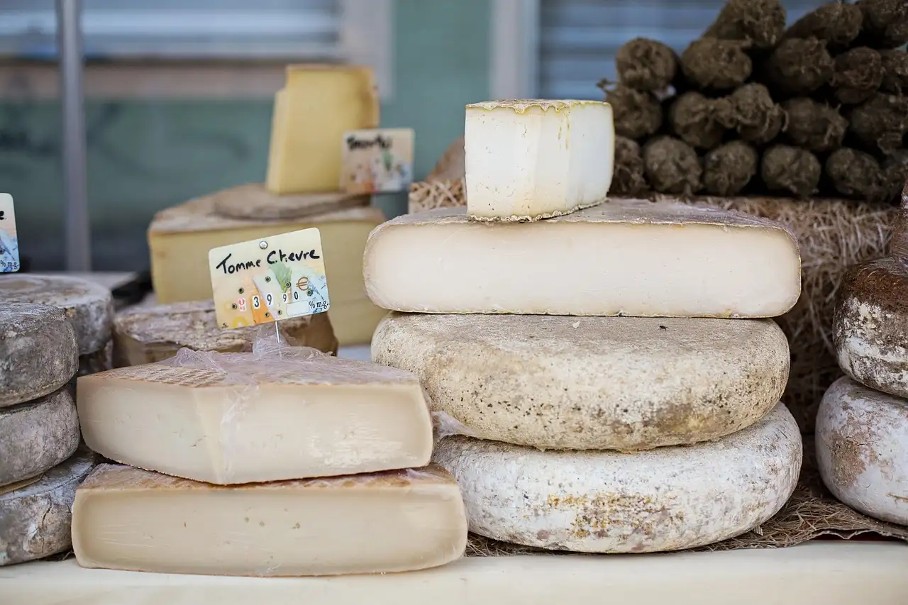 Wheels of cheese stacked on a market counter