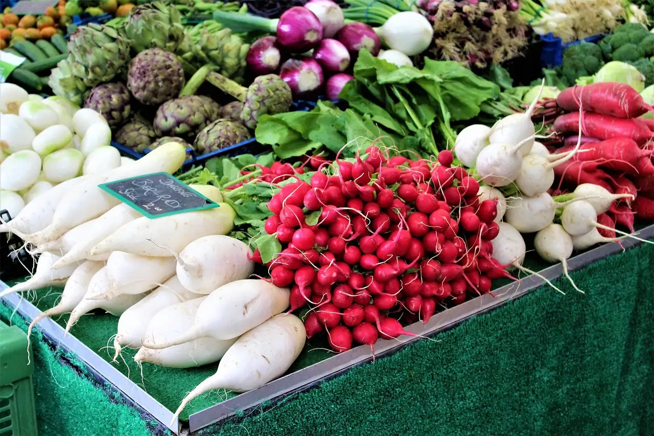 Bunches of red radishes and white radishes piled on a market stall at the Viktualienmarkt