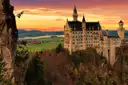 Neuschwanstein Castle on its hill at sunset, with autumn trees below