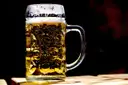 A full glass beer mug with foam on a table