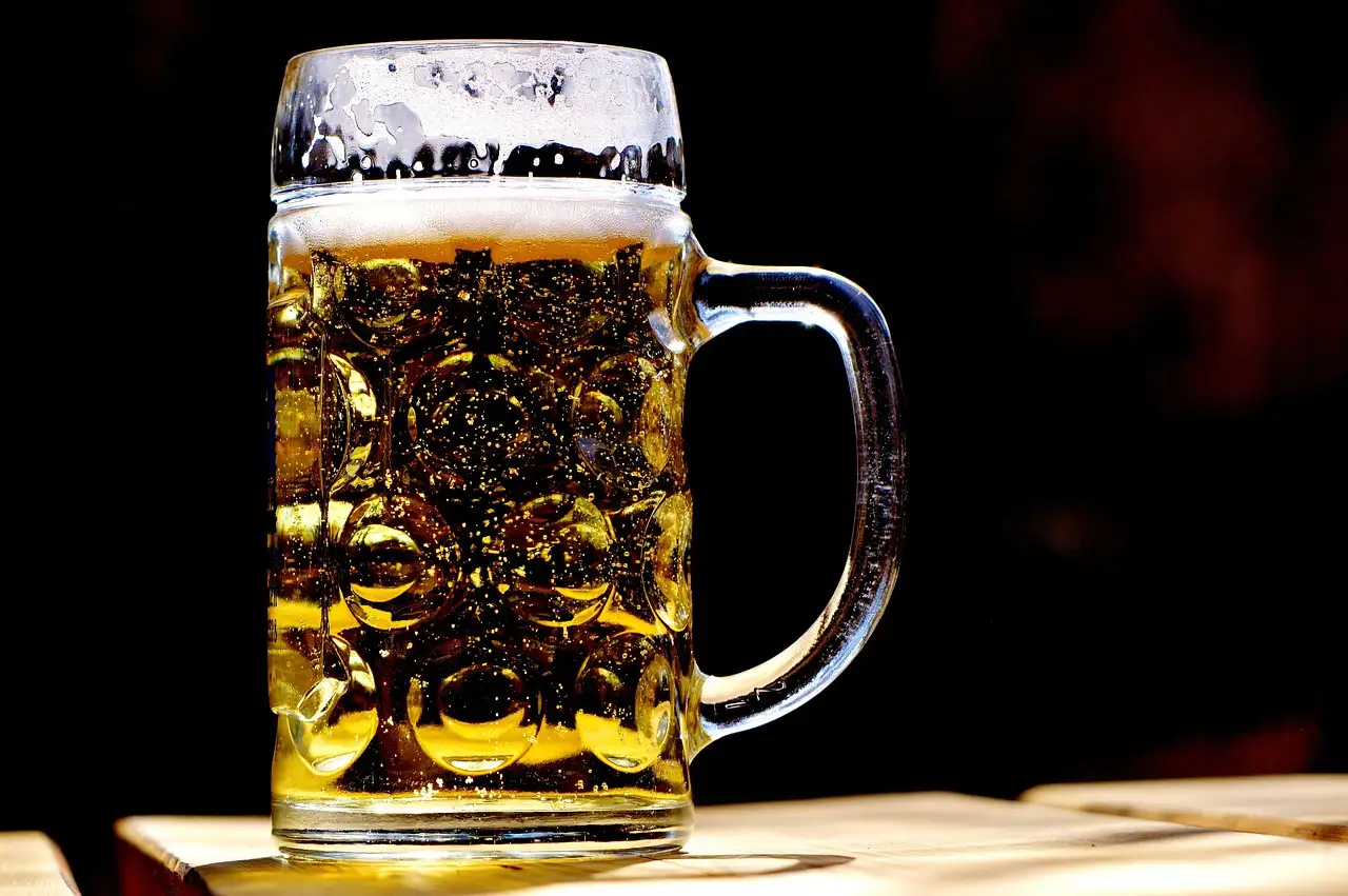 A full glass beer mug with foam on a table
