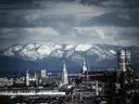 The Frauenkirche towers and Old Town of Munich with snow-capped Alps behind under dark clouds
