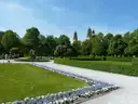 Flower beds and paths in the Court Garden in summer, with church towers behind the trees