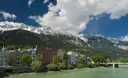 Colorful houses along the Inn River in Innsbruck, with snowy mountains behind