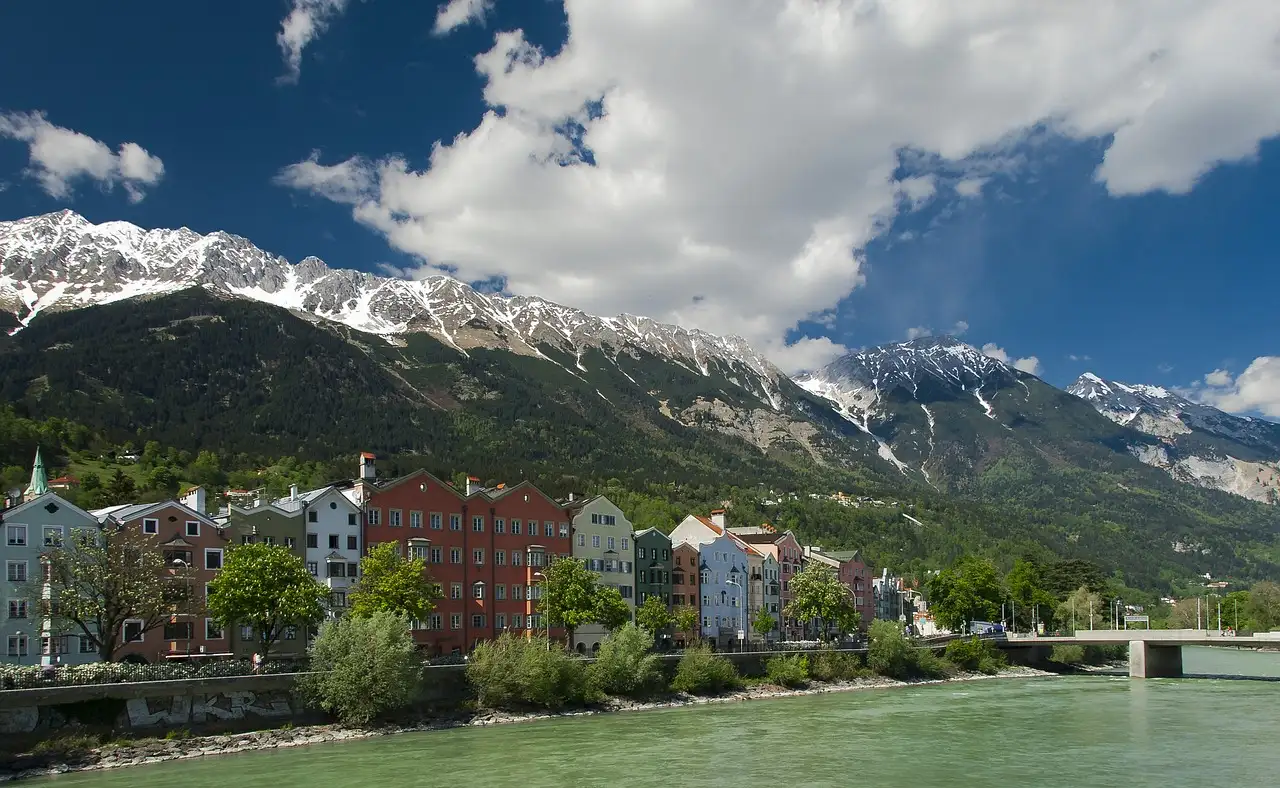Colorful houses along the Inn River in Innsbruck, with snowy mountains behind